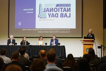 A panel of National Lab scientists talk under a slide that says "主要研究 DOE 国家实验室日