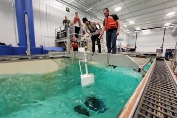 Students wearing life vests stand at the edge of a test tank